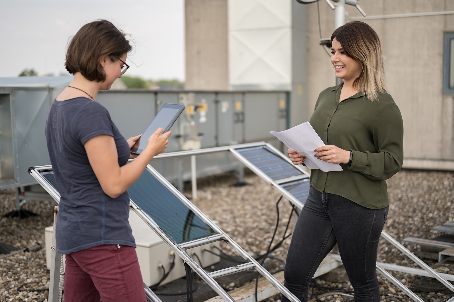 Zwei Studentinnen auf dem Dach vor den Solaranlagen